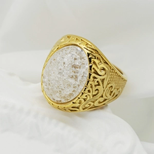 Dettaglio macro di un anello vintage dorato con pietra bianca e incisioni ornate