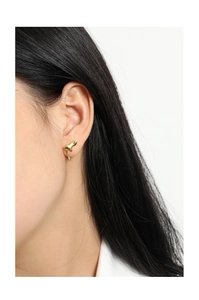 Close-up of minimalist gold liquid-style earrings worn by a model in a side view