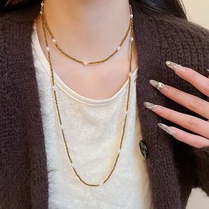 Detail of beaded long necklace with tiger eye stones and white pearls on a sweater