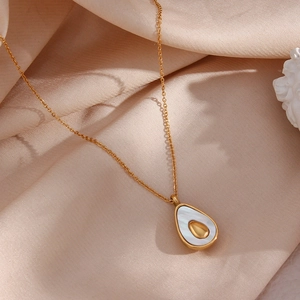 Close-up of gold avocado pendant with white shell inlay on elegant champagne silk