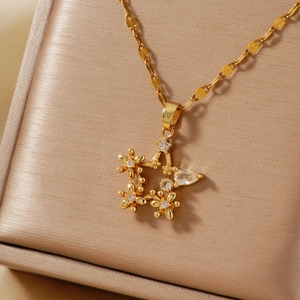 Elegant gold star pendant necklace with cubic zirconia floral details on beige silk box