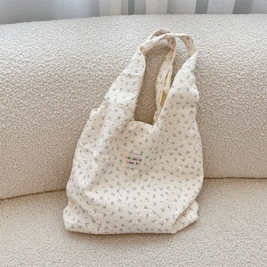 Close-up of cream floral tote bag with bubble pleat texture and sozakka label detail