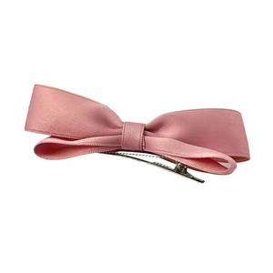 Close-up of pink satin bow hair clip featuring a secure silver metal duckbill fastener