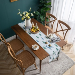 Nordic style Christmas table runner with reindeer and pine patterns on a wooden dining table
