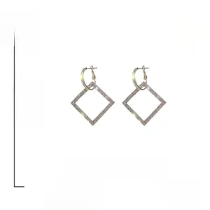 Dettaglio di orecchini geometrici quadrati dorati con pavé di cristalli e perni in argento 925