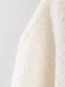 Detailed close-up of cream white curly faux fur fabric and stitching on a winter coat