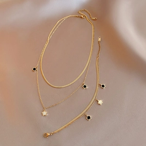 Ensemble collier double rang et bracelet étoile doré posé sur un tissu de soie