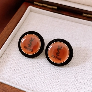 Close-up of retro acrylic round stud earring with gold metal inlay and logo detail