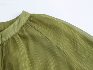 Detailed macro view of grass green chiffon fabric with gold silk stripes and pleated texture
