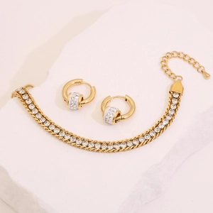 Detail of gold stainless steel bracelet and earrings set with sparkling white crystals