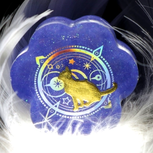 Macro shot of purple resin cat paw charm with gold cat silhouette and holographic magic circle