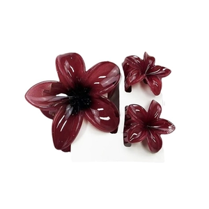 Three-piece set of burgundy plumeria flower hair claws on a white card background