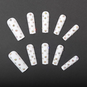 White coffin press-on nails set with vibrant colorful rhinestones on black background