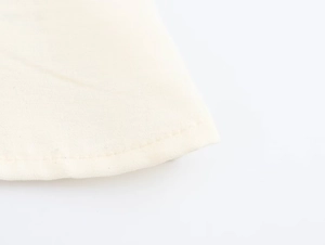 Close-up of beige fabric edge showing fine stitching and premium textile texture
