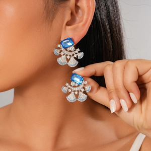 Macro view of crystal drop earrings with blue square gems and fan-shaped diamond pavé