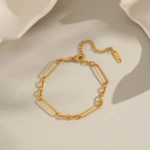 Detail of gold double-layer chain bracelet with lobster clasp on a minimalist stone base
