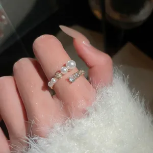 Elegant gold-plated open ring with pearls and zircon crystals worn by a model