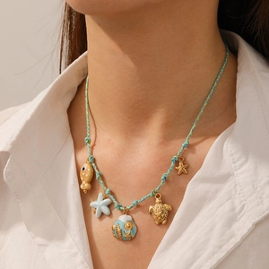 Close-up of woven ocean necklace with gold sea turtle, starfish, and shell charms