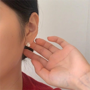 Detail view of 925 sterling silver bowknot pearl earrings worn on a female earlobe