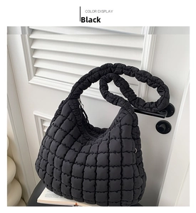 Detail of black quilted puffer bag showing wrinkled shoulder strap and cloud design