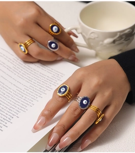 Close-up of gold and silver evil eye rings with blue enamel detail worn on a model's hand