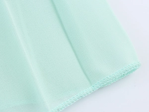 Close-up of light green chiffon fabric edge with high-quality overlock stitching details