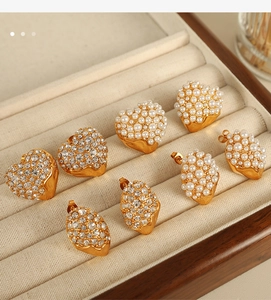 Macro detail of 18K gold-plated earrings with pavé pearls and rhinestones on velvet