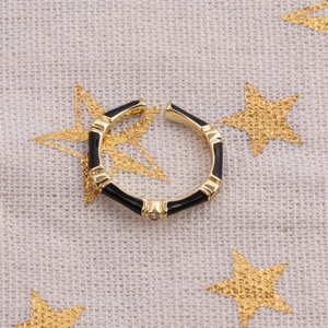 Close-up of a gold bamboo-style open ring with black enamel and sparkling zircons