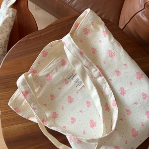 Close-up of floral cotton tote bag fabric texture and inner woven label on wooden stool