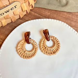 Detailed macro view of woven raffia fan-shaped earrings with amber resin accents