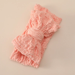 Detail of pink stretch baby headband featuring oversized bow and 3D textured knit fabric