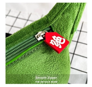 Detail of green plush bag with smooth plastic zipper and red lucky rabbit charm