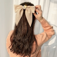 Detailaanzicht van een grote beige haarstrik met vierkante kristal op lang haar