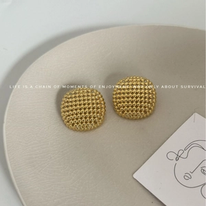 Luxury gold hollow mesh ball stud earrings in vintage style on a ceramic plate