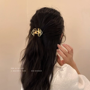 Elegant gold metal hair claw with pearl detail on dark hair, vintage French hair clip