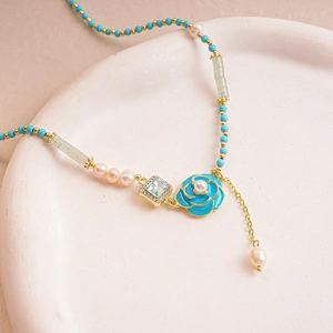 Close-up of blue enamel flower necklace with freshwater pearls and golden tassels