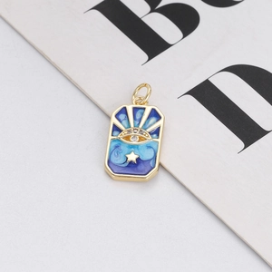 Macro shot of rectangular gold charm with blue enamel eye and star inlay details