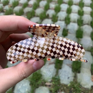 Classic checkered large acetate shark hair claw clip for women held outdoors
