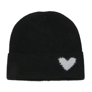 Close-up of black knitted beanie featuring a white fuzzy heart patch decoration