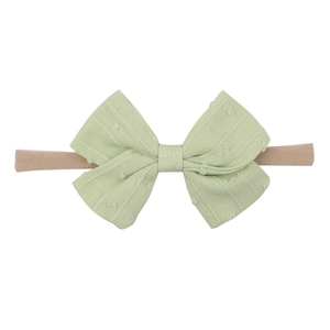 Detail of light green bow baby headband with jacquard texture and high-stretch nude band