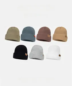 Detail view of seven knitted beanies with ribbed texture and brown leather logo patches