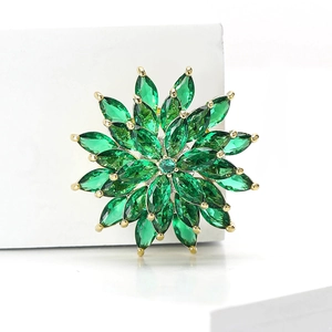 Close-up of elegant gold brooch featuring a spinning green zircon snowflake design