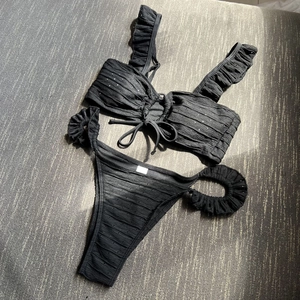 Detailed view of black ruffled bikini set with lace-up front and textured micro-perforated fabric