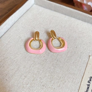 Detail shot of pink U-shaped floral earrings with gold accents on a textured jewelry tray