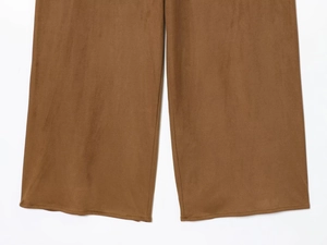 Détail du pantalon large en daim marron montrant la texture du tissu et l'ourlet