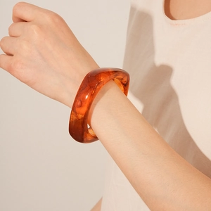 Macro detail of amber resin bangle showing semi-transparent marble texture and warm tones