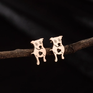 Macro shot of rose gold puppy earrings with heart cutout on a natural wooden branch