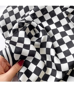 Detailed view of black and white checkerboard silk scarf with soft drape texture