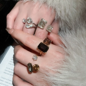 Close-up of geometric zircon rings in various cuts worn with elegant faux fur cuff