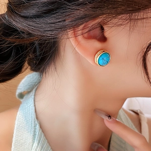 Close-up of vintage turquoise stud earring with gold plating and cubic zirconia on ear